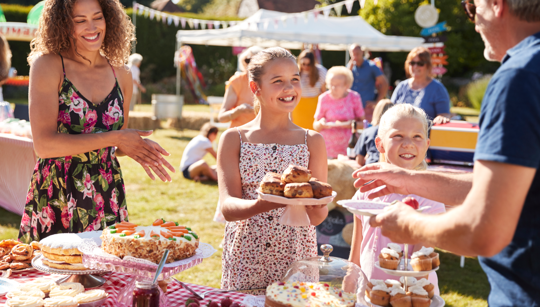 A group of people are standing around a table holding plates of food.