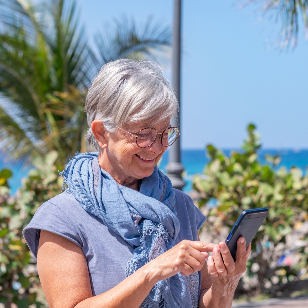 An older woman wearing glasses and a scarf is looking at her cell phone.