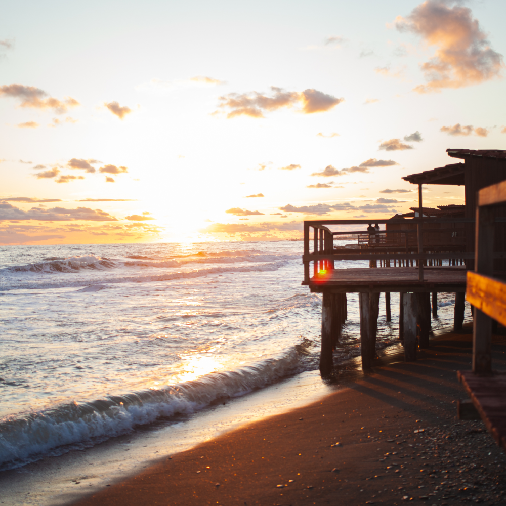 A sunset over the ocean with a dock in the foreground