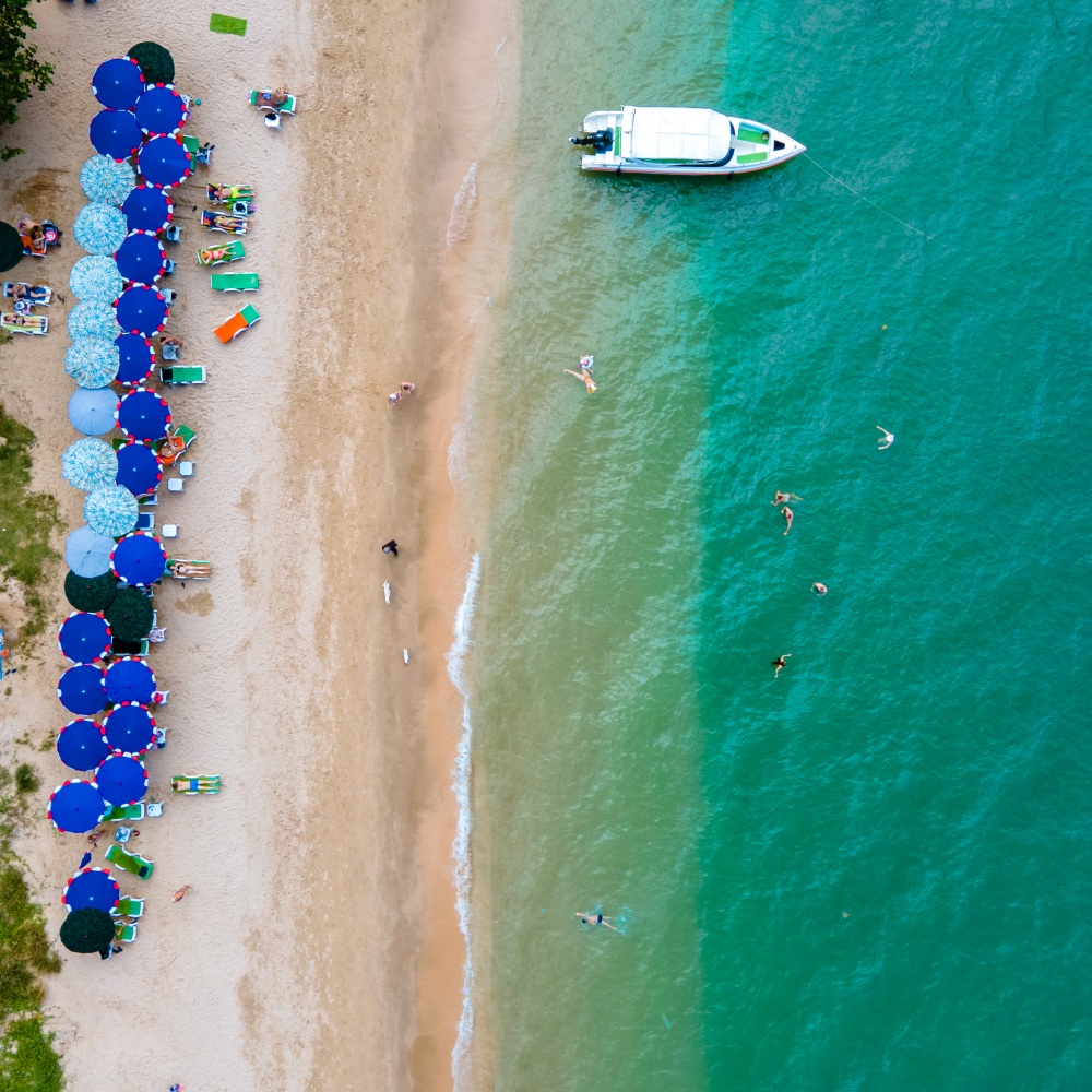 An aerial view of a beach with umbrellas and a boat in the water