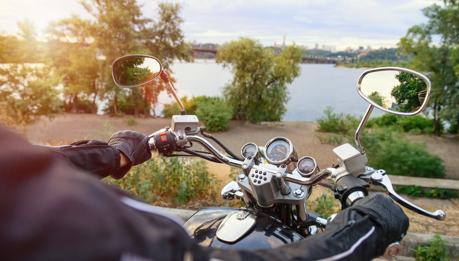 A person is riding a motorcycle on a road next to a body of water.