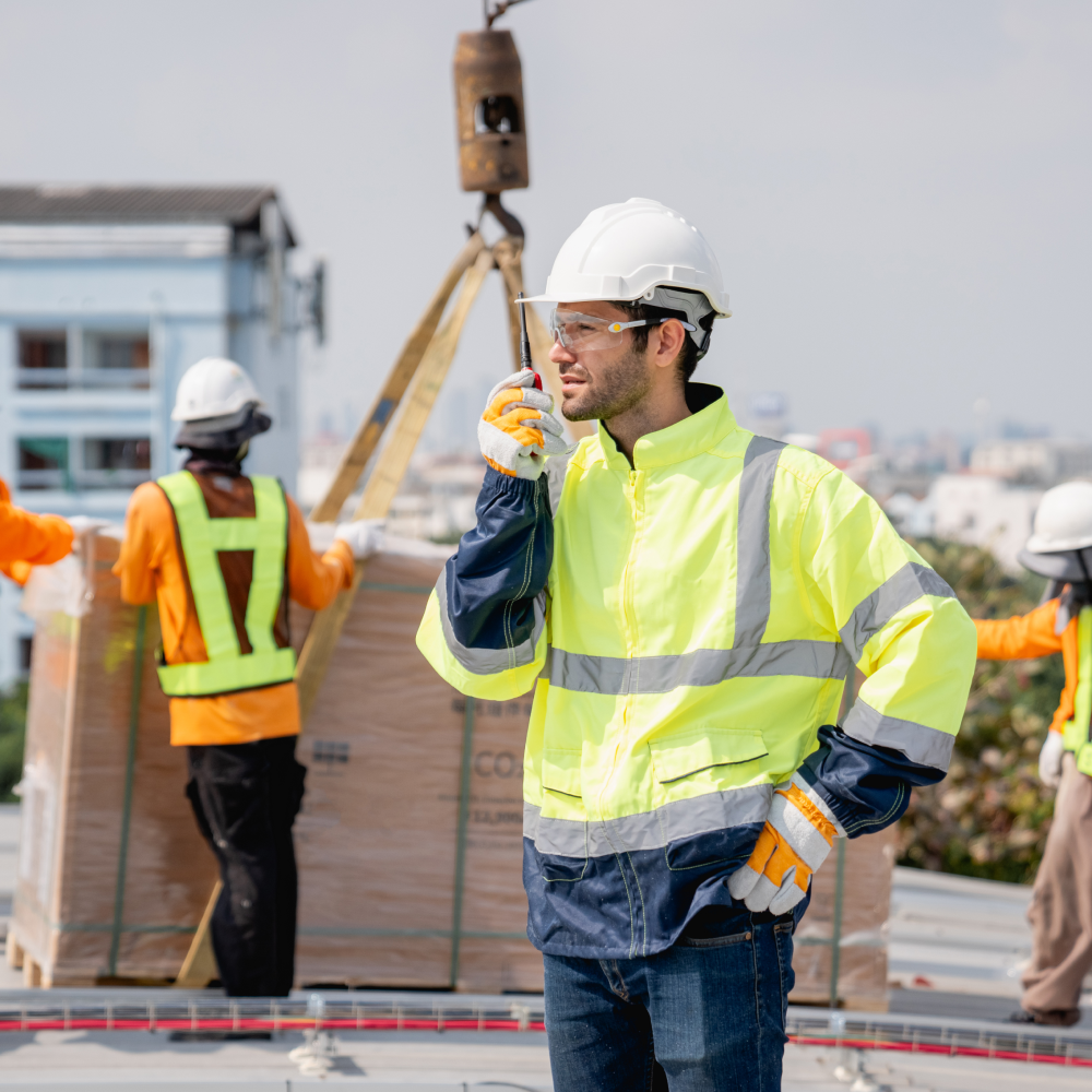 A man wearing a hard hat and safety vest is talking on a cell phone.
