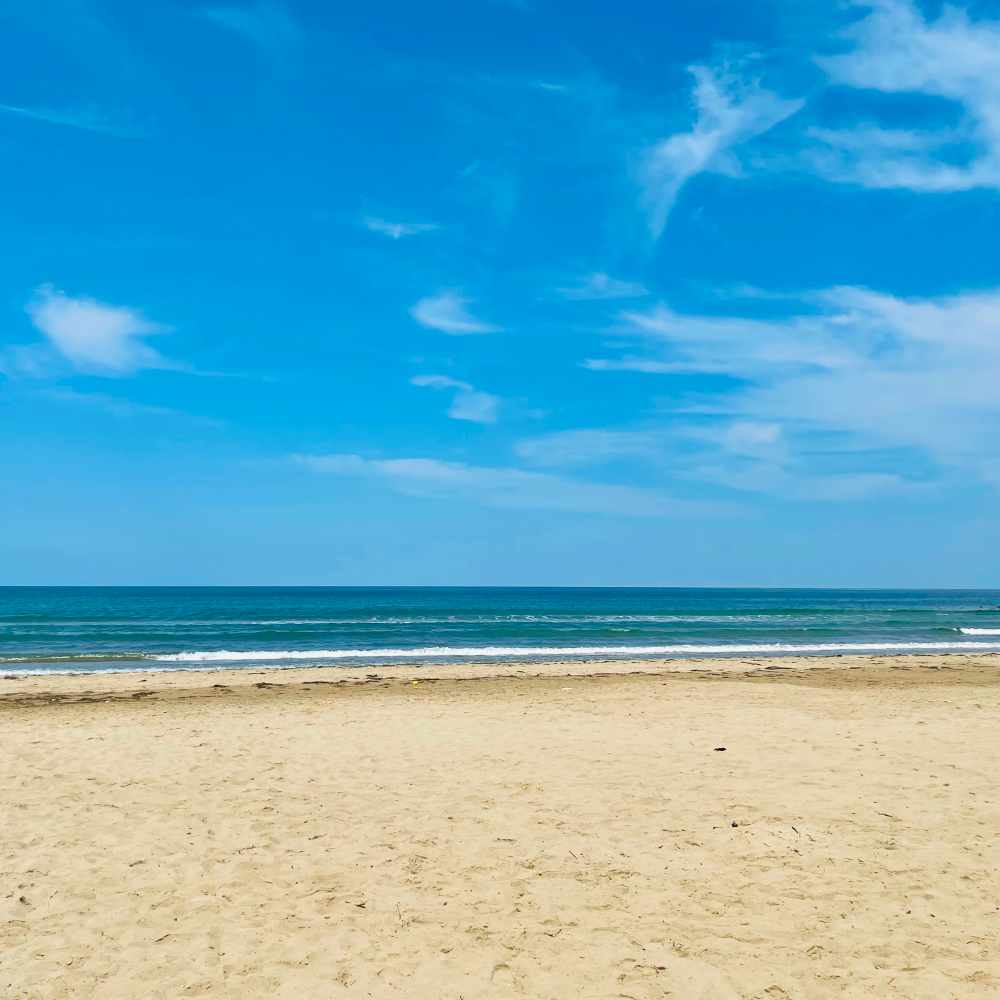 An empty beach with the ocean in the background on a sunny day.