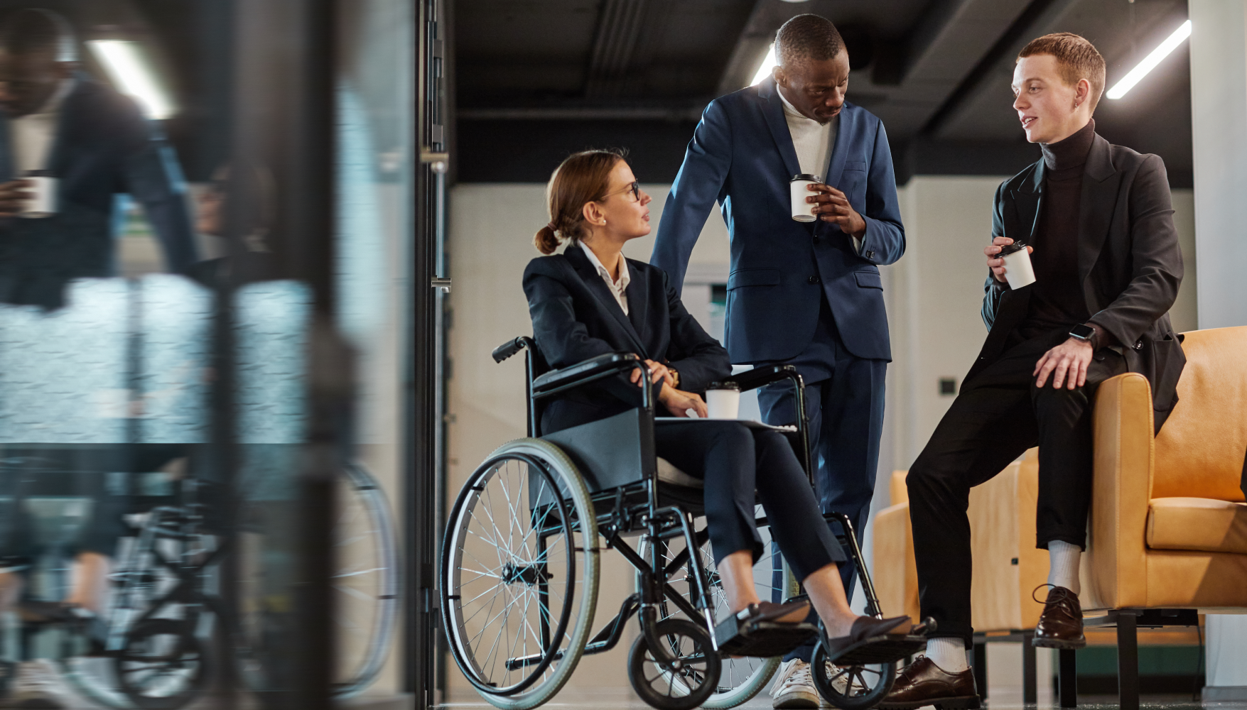 A woman in a wheelchair is talking to two men in suits.