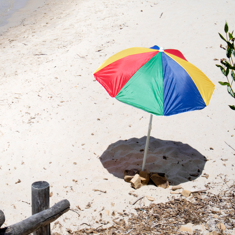 A colorful umbrella sits on a sandy beach