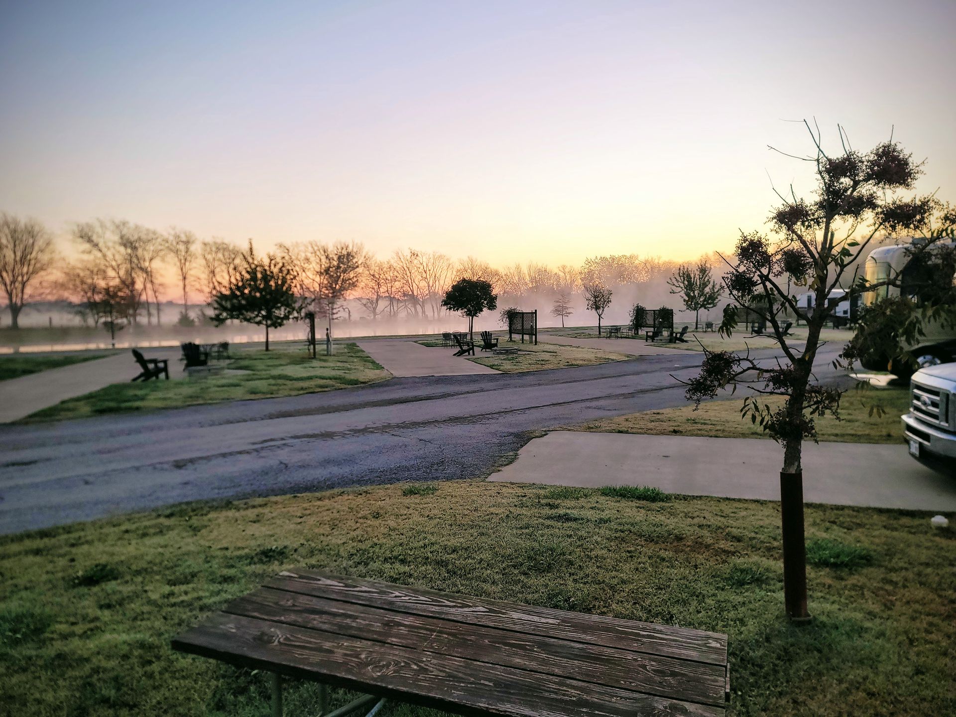 a picnic table is in the middle of a park at sunset