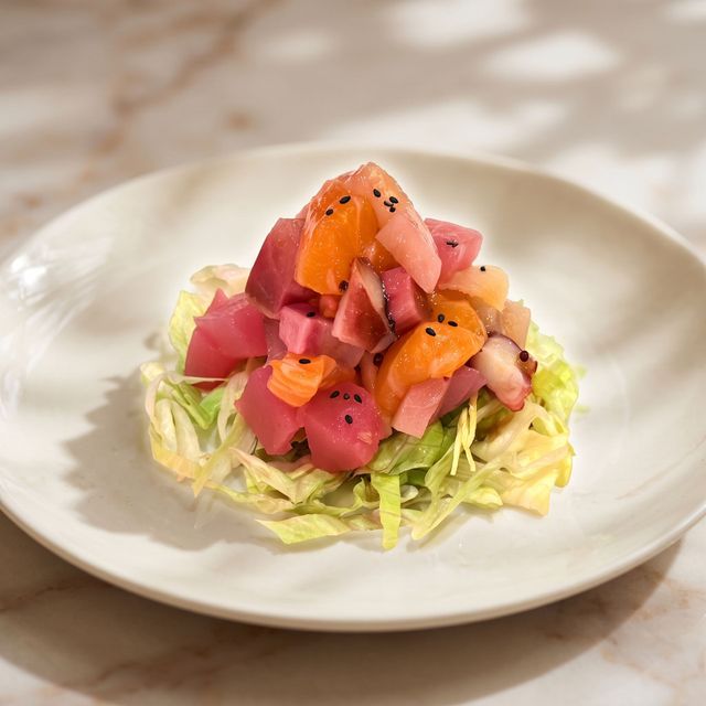 Diced fish and vegetables stacked over shredded lettuce on a white plate