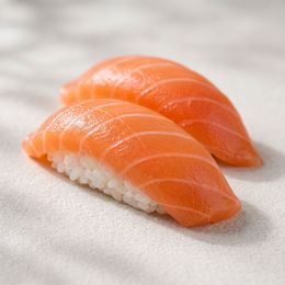 Two pieces of salmon nigiri sushi on a white surface