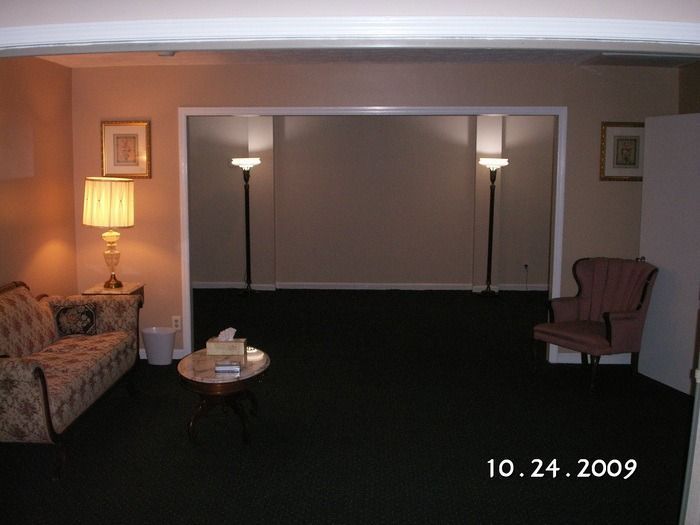 Dim living room with couch, lamps, coffee table, and sliding glass doors at night.