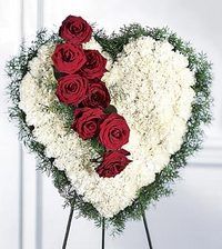 Heart-shaped floral arrangement with white and red roses on a stand