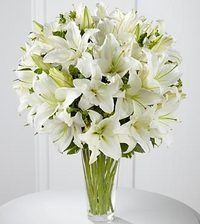 White lilies in a clear glass vase on a table