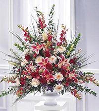 Large colorful floral arrangement with pink, red, white, and yellow flowers in a white vase