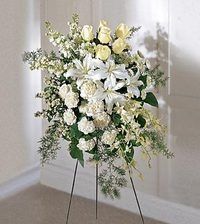 White and cream floral arrangement on a black metal stand in a corner against a light wall