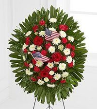 Floral funeral wreath with red, white, and green flowers and small American flags