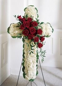 White floral cross with red roses on a stand