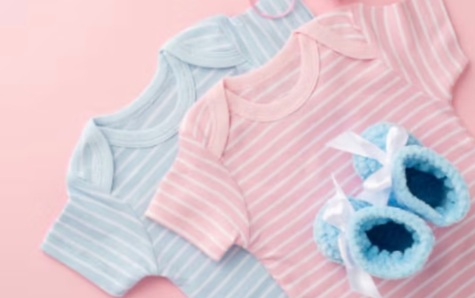 Pastel baby onesies and blue booties on a pink background