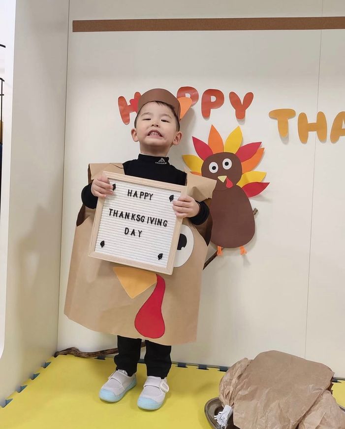 Un ragazzino in costume da tacchino tiene in mano un cartello con la scritta 