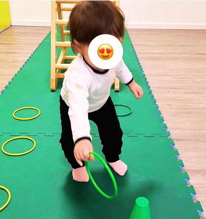 Un bambino sta giocando con un anello verde e un cono verde