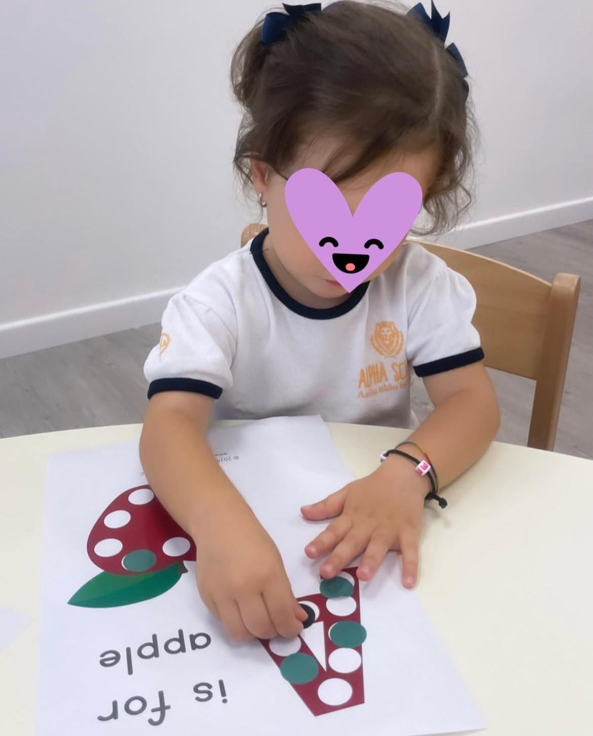 Una bambina con un cuore sul viso sta giocando con una mela