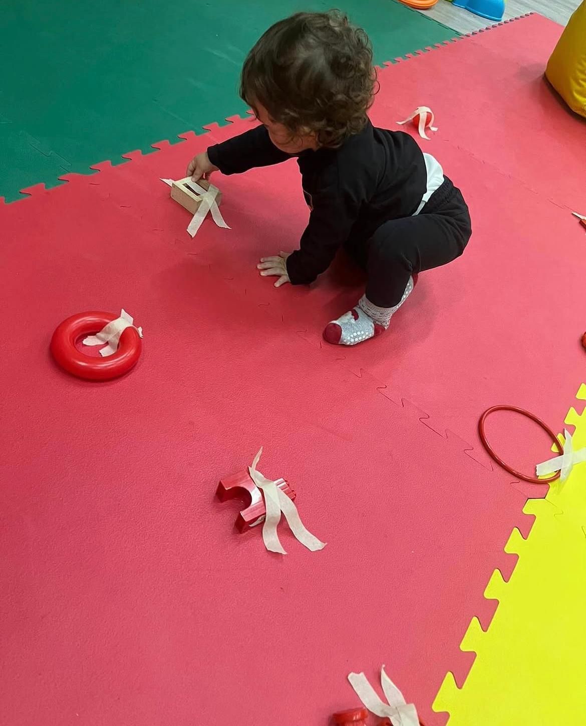 Un bambino sta giocando con un anello rosso sul pavimento