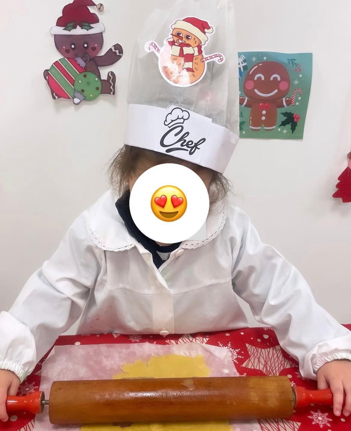 Una bambina indossa un cappello da cuoco e un mattarello