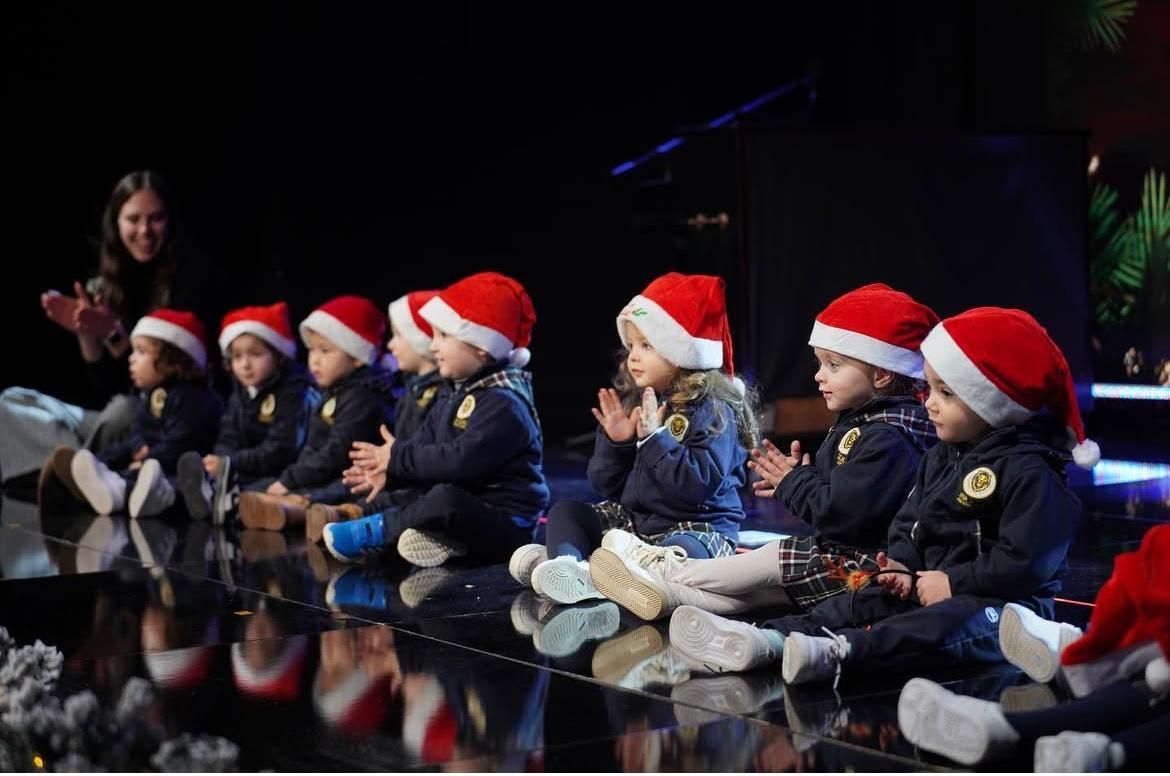 Un gruppo di bambini seduti su un tavolo indossano cappelli da Babbo Natale.