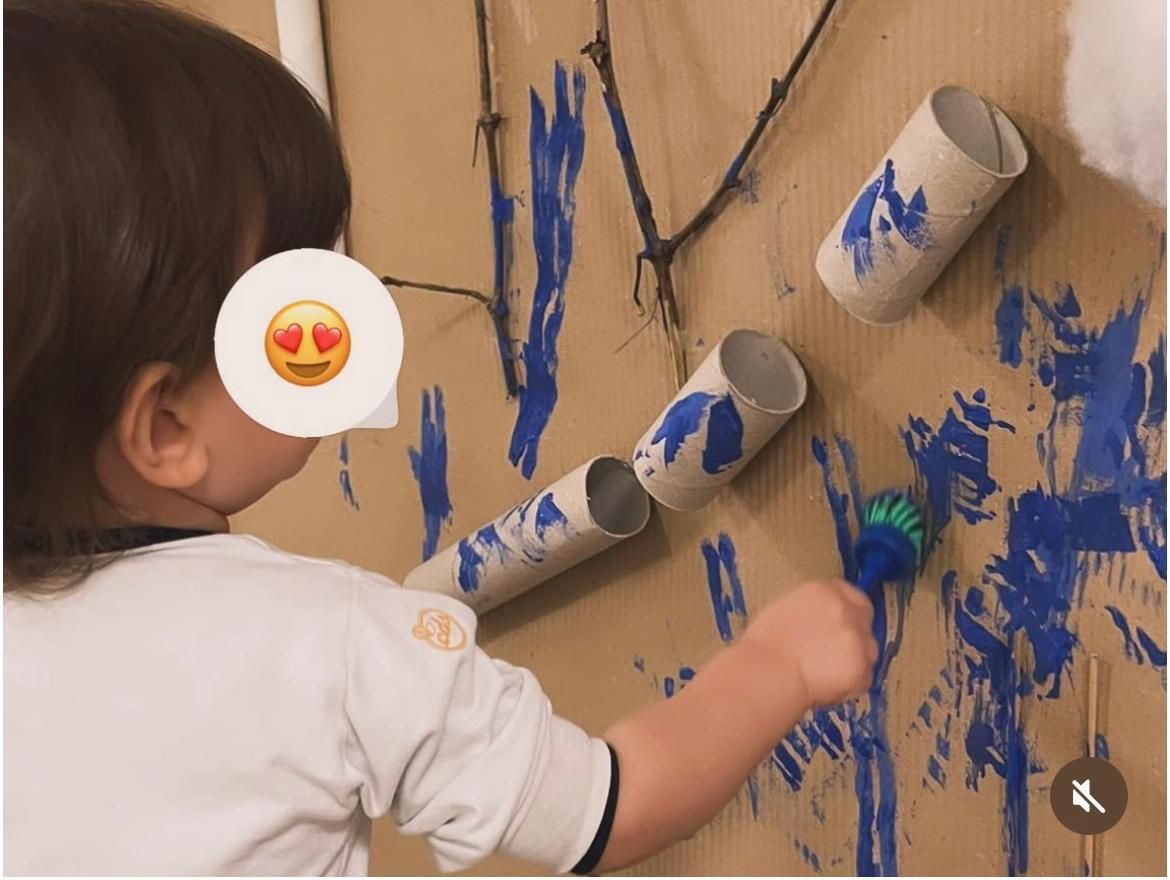 Un bambino sta giocando con i rotoli di carta igienica su una parete di cartone.