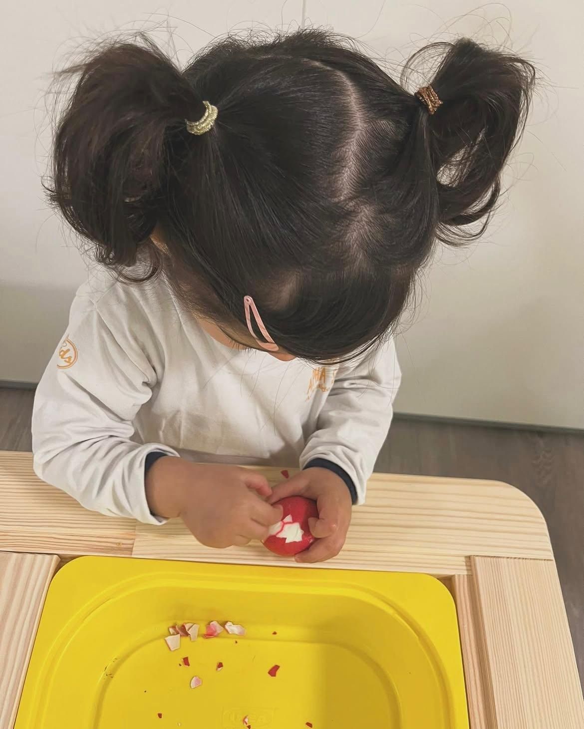 Una bambina sta giocando con una palla rossa su un tavolo.