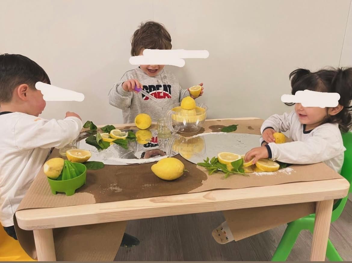 Un gruppo di bambini è seduto a un tavolo con sopra dei limoni.