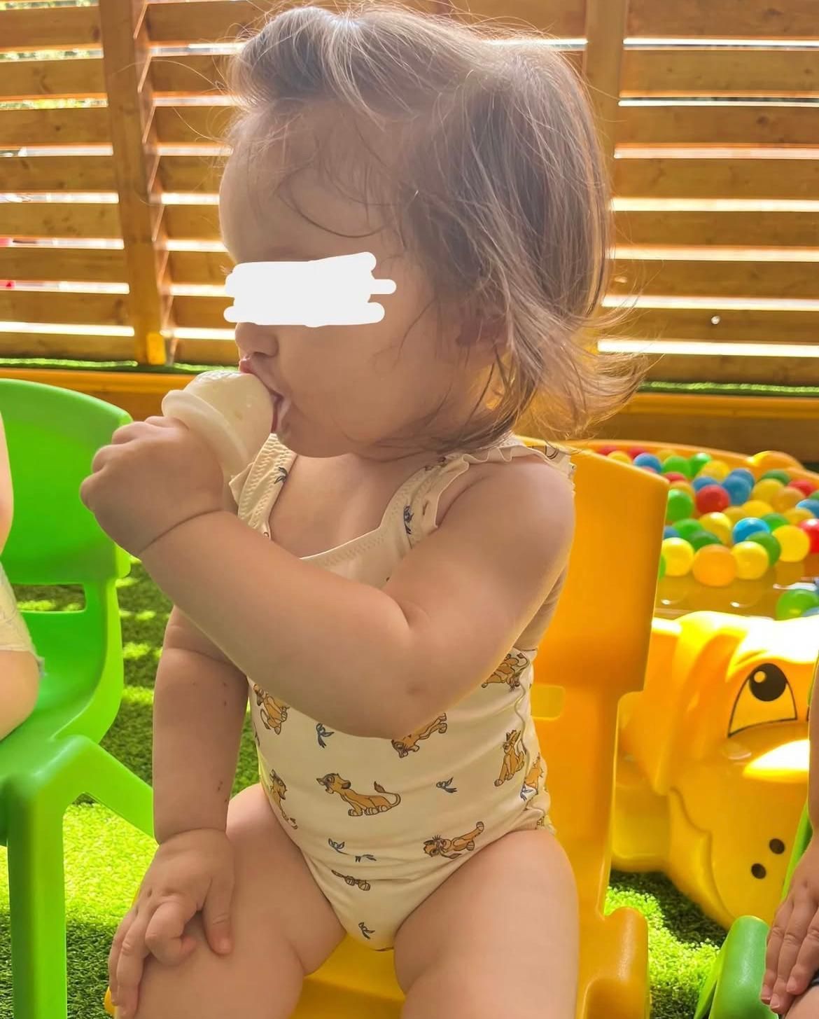 Una bambina è seduta su una sedia gialla e mangia un cono gelato.