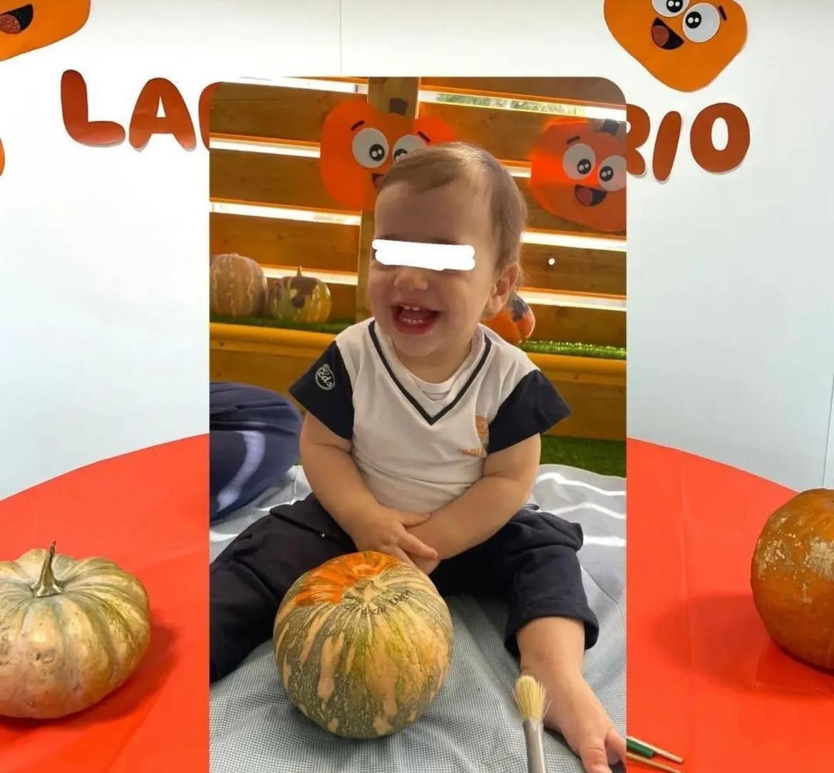 Un bambino è seduto su un tavolo con una zucca davanti a un cartello che dice la rio