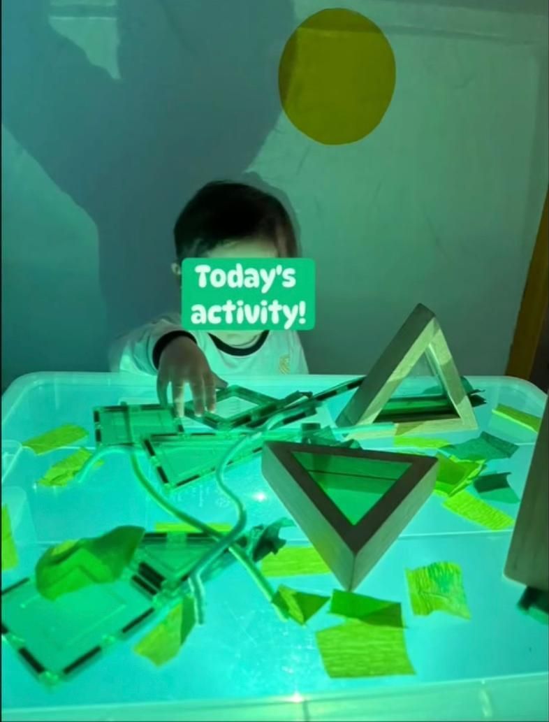 Un bambino sta giocando con i triangoli e un cartello che dice l'attività di oggi