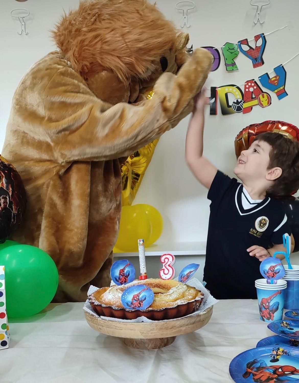 Una mascotte leone che fa il cinque a un bambino a una festa di compleanno