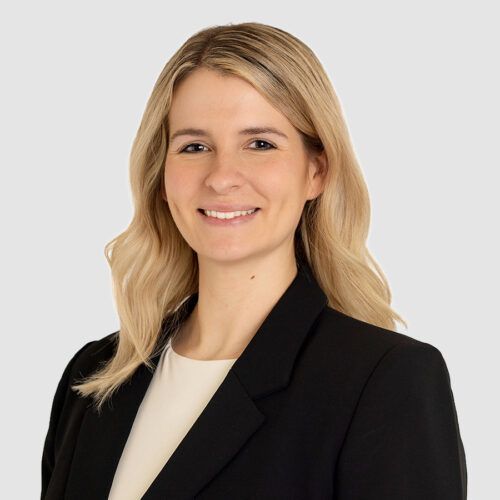 Amanda Snyder, smiling, wearing a black blazer and white top, against a grey background.