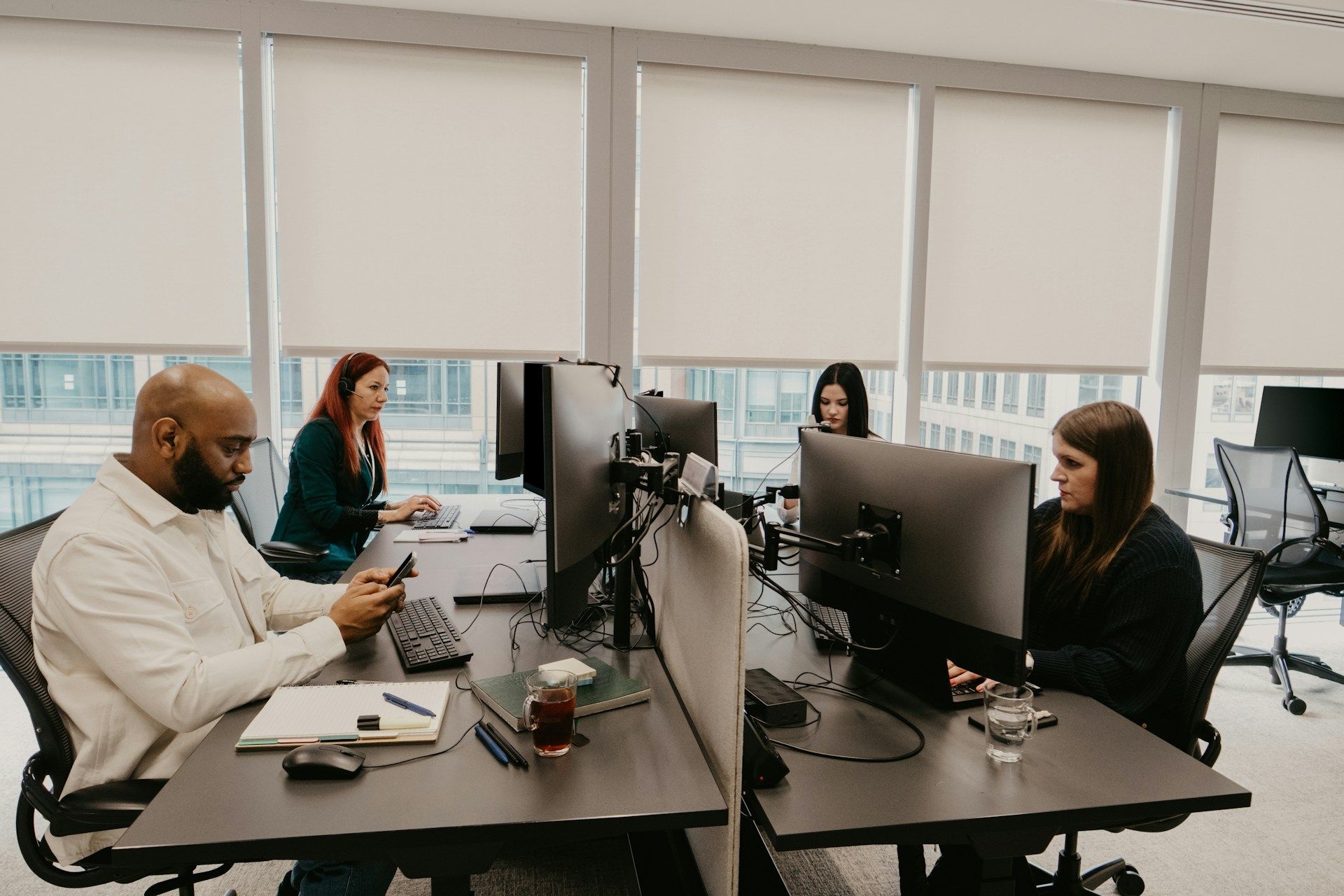 Business team meeting around a table, collaborating on papers and a laptop in a brightly lit office.
