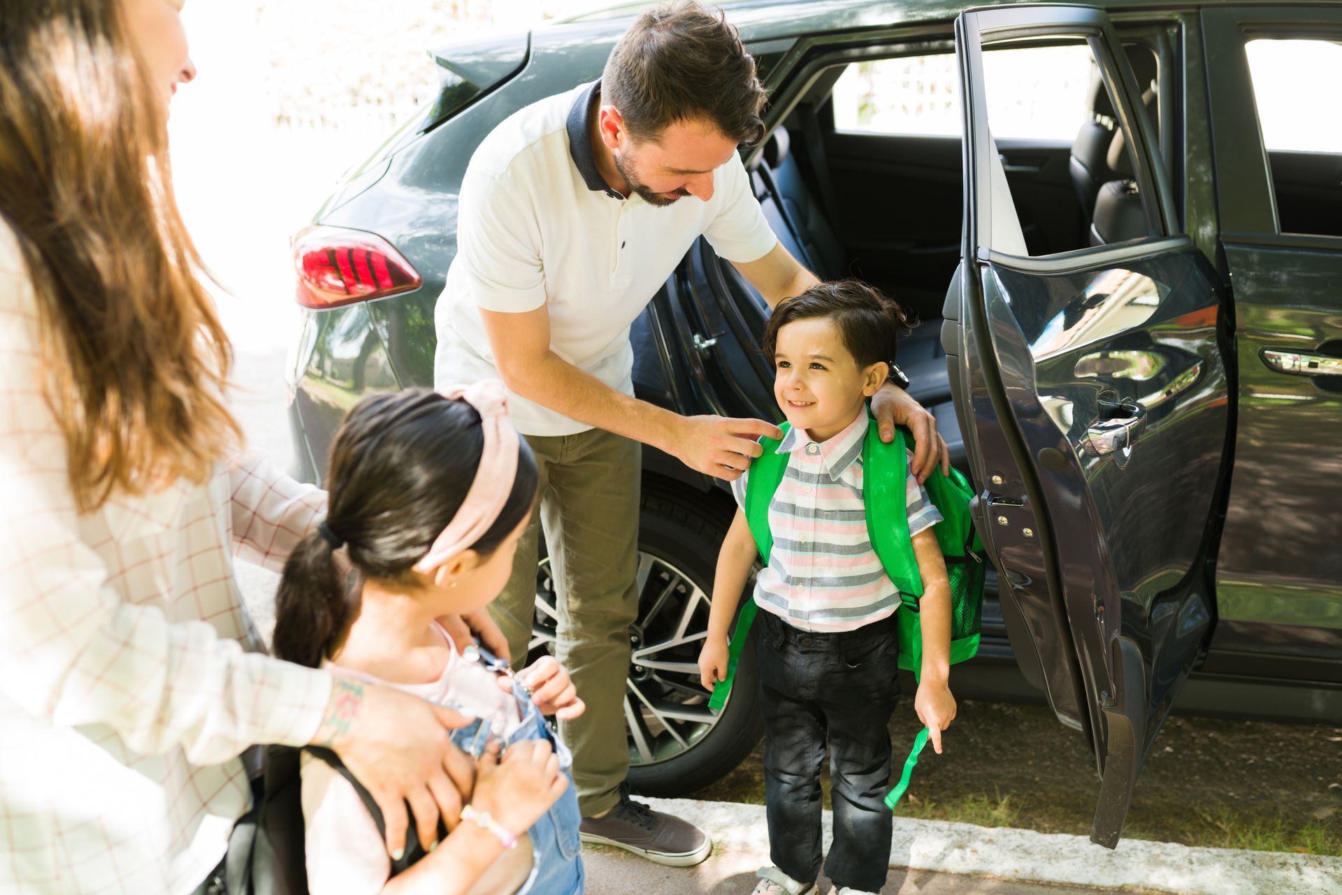 Family loading children with backpacks into a car.
