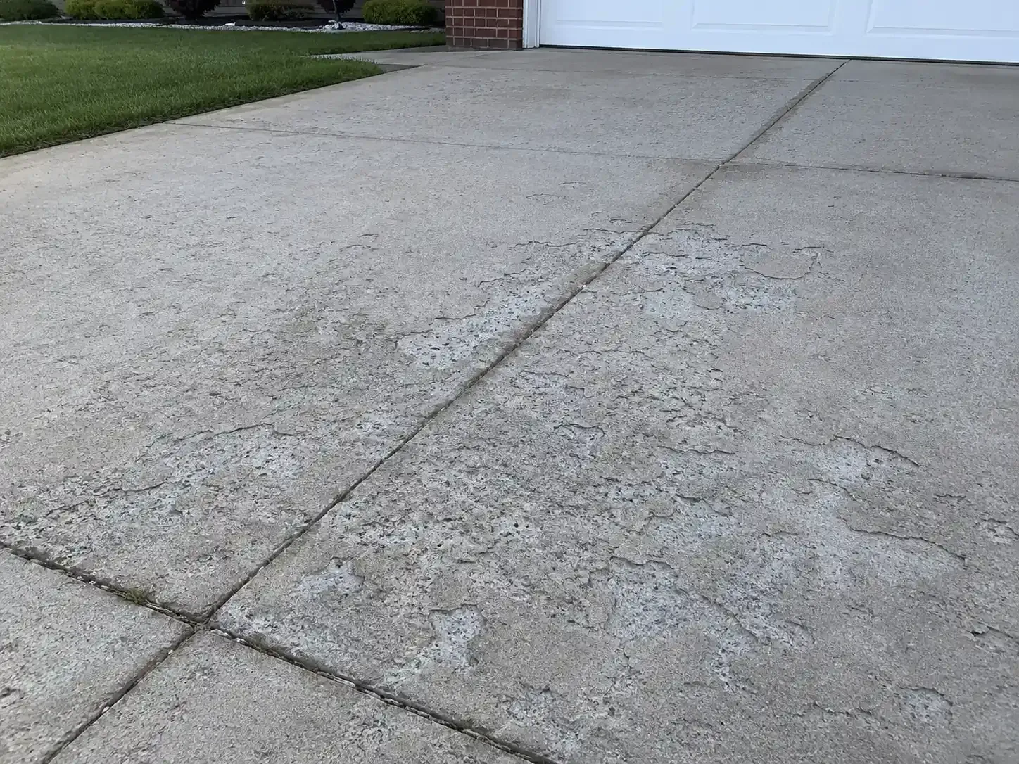 Concrete driveway with peeling and flaking leading to a garage
