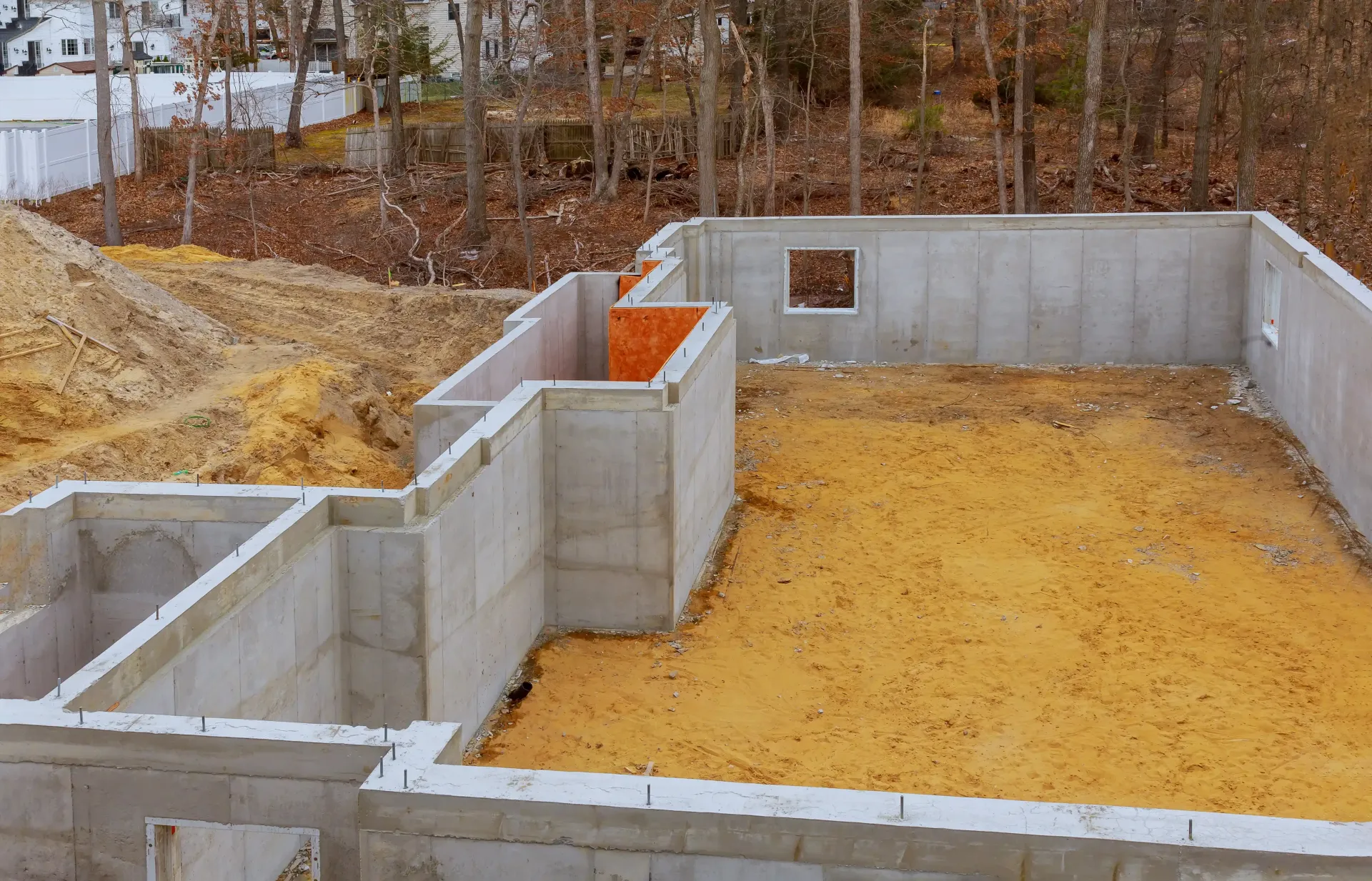 Foundation walls for a house under construction, with concrete footings and a dirt-filled interior lot.