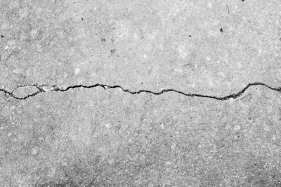 Cracked gray concrete surface with a thin horizontal fissure across the center