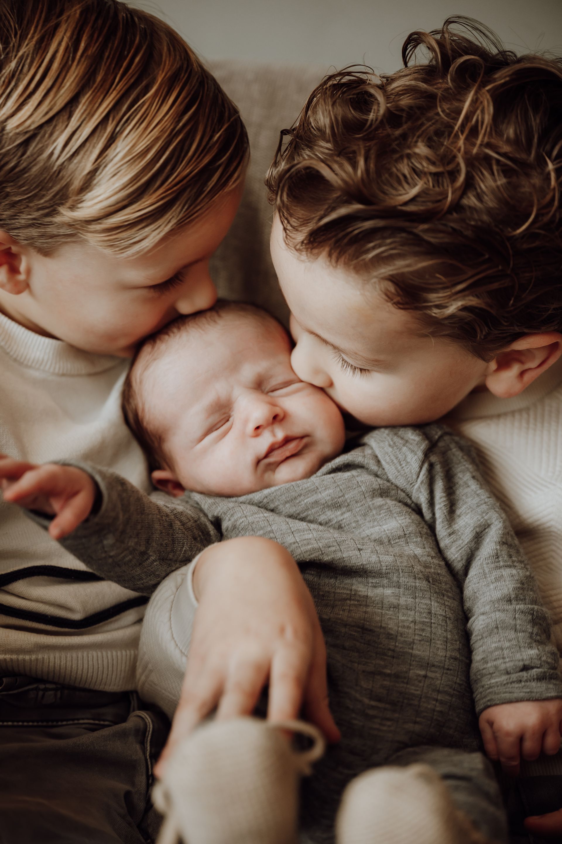 Een slapende baby in een donker gebreid truitje, gewiegd in iemands armen. Newborn
