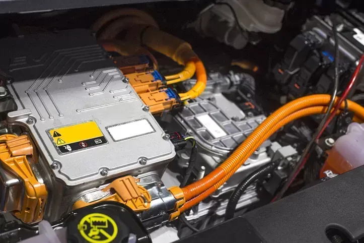 Electric vehicle battery pack with orange high-voltage cables and silver components in a car engine bay