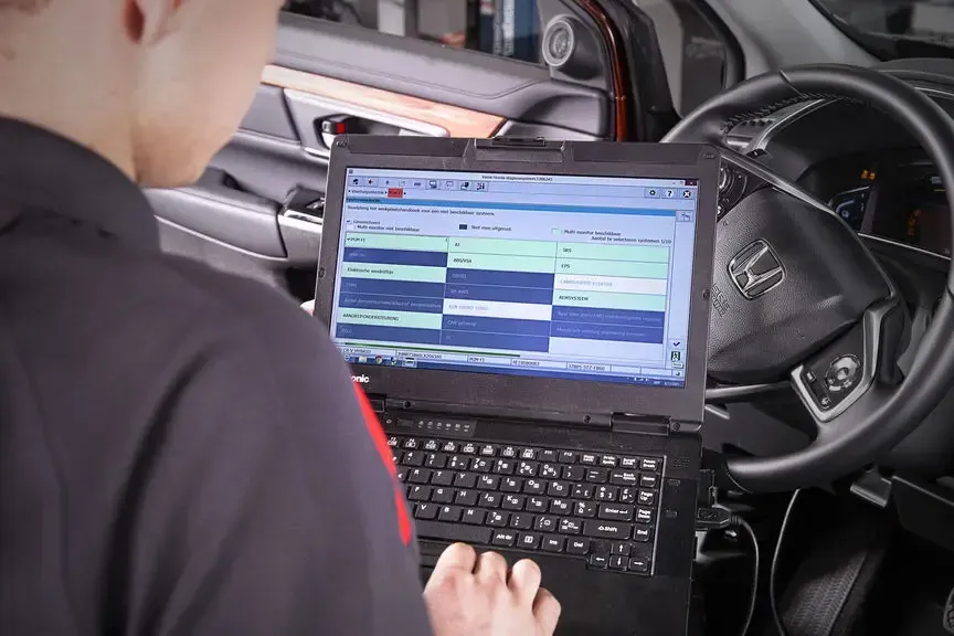 Person using a laptop in a car, viewing a schedule screen on the dashboard area