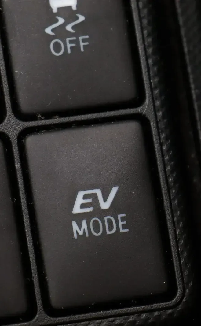 Close-up of black car dashboard buttons labeled EV MODE and OFF.