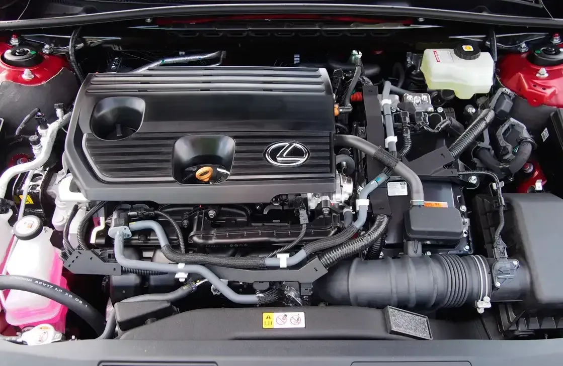 Car engine bay with a black Lexus engine cover and visible hoses, battery, and red strut towers.