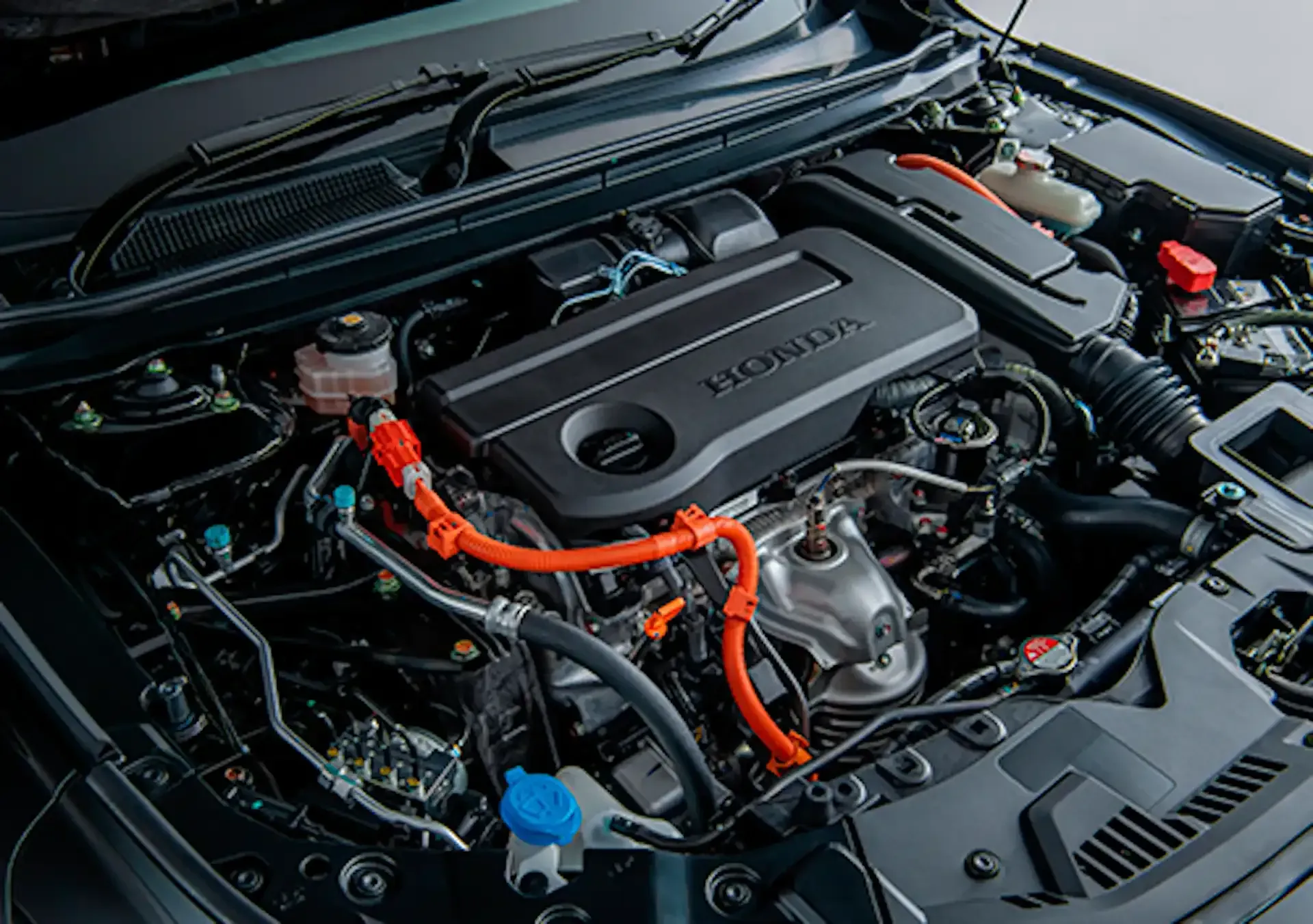 Honda car engine bay with orange cables and visible components under the hood