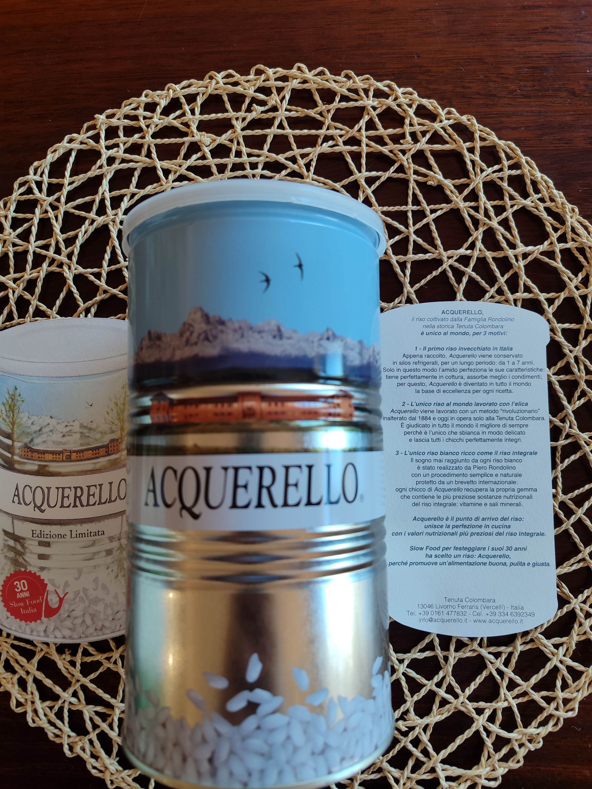 Candela Macquerelo con coperchio blu, al centro di una tovaglietta intrecciata accanto a delle schede prodotto