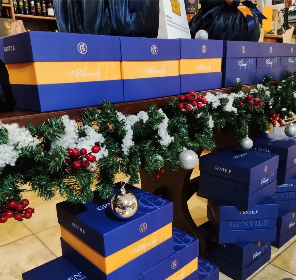 Scatole regalo blu con nastri arancioni, decorate con ghirlande natalizie e addobbi, in un ambiente interno