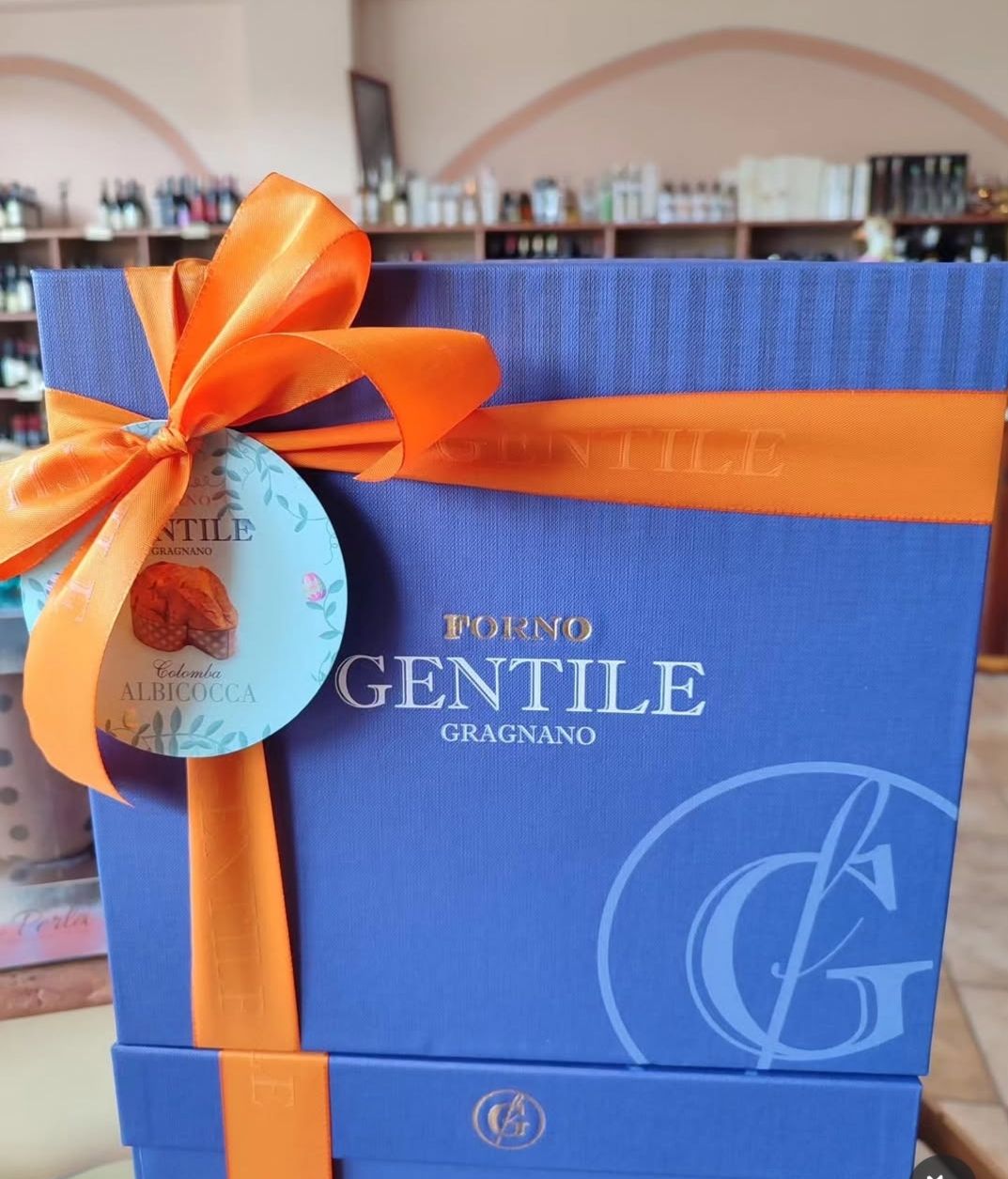 Sacchetto regalo blu con nastro e fiocco arancioni, con l’etichetta «Domenico Gentile», in un negozio