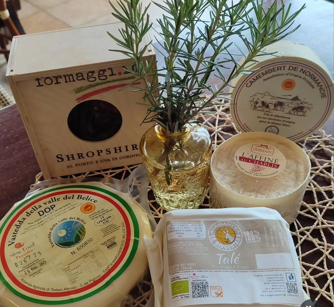 Confezioni assortite di prodotti artigianali e un piccolo rametto di erbe aromatiche in un vaso di vetro su un tavolo.