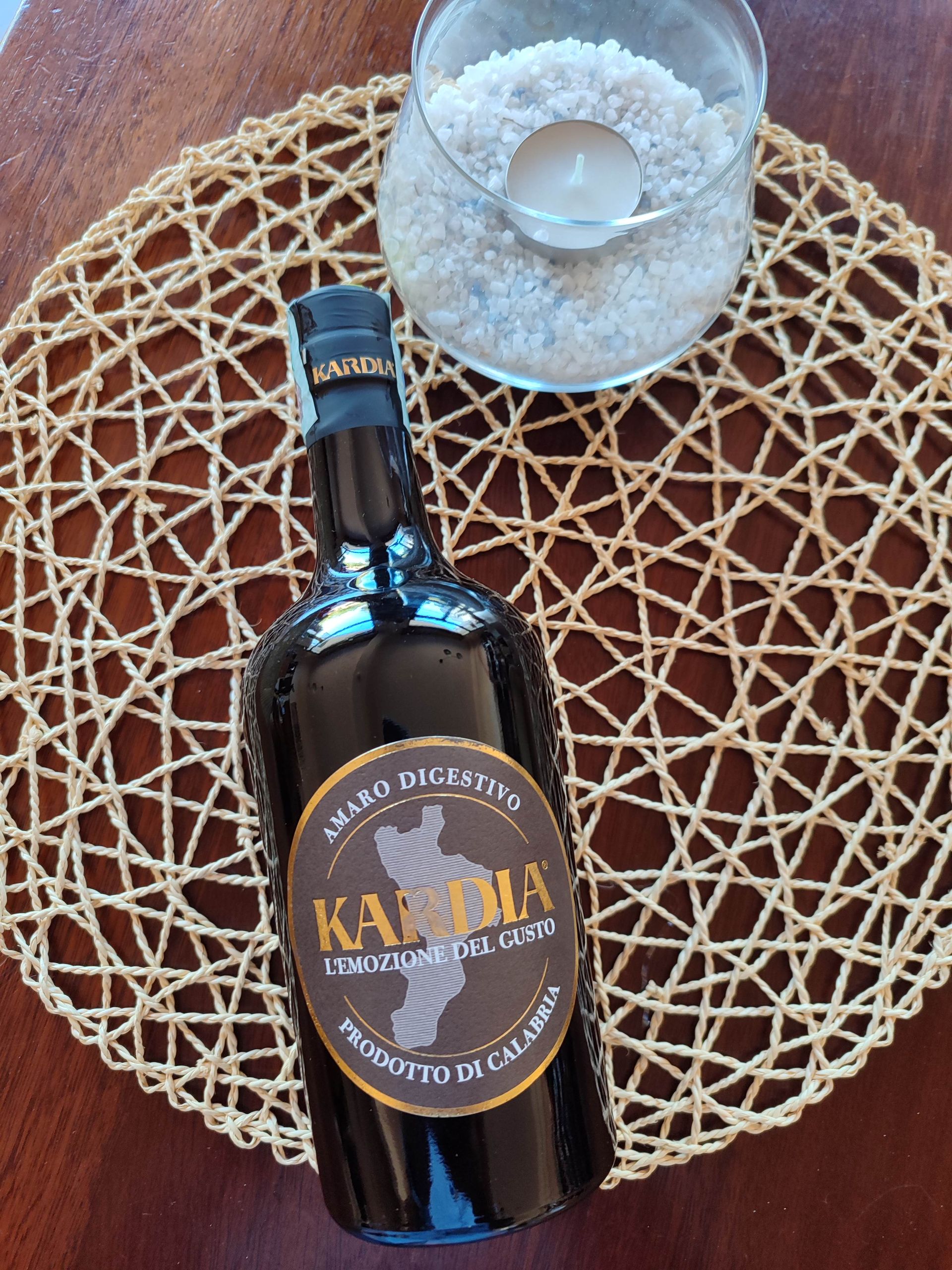 Bottiglia scura con l’etichetta “Kahlúa” su una tovaglietta intrecciata, accanto a una ciotola di ghiaccio e a un cucchiaio.